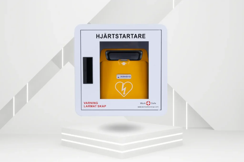 Vitt värmeskåp för hjärtstartare med orange hjärtstartare inuti, märkt med 'HJÄRTSTARTARE' och varningstext 'VARNING LÄRMAT SKÅP'.