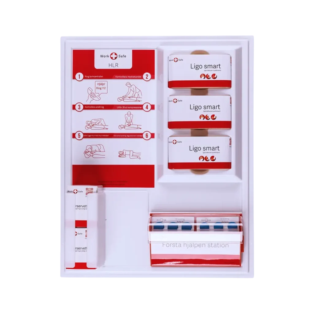 En väggmonterad första hjälpen-tavla från Work Safe, komplett med instruktioner för hjärt-lungräddning (HLR), självhäftande förband, plåster och sårrengöring. Designad för enkel tillgång i nödsituationer och arbetsmiljöer.
